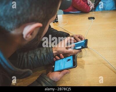 Paris, France - Nov 3, 2017: Overhead view of two Male friends customers admiring inside Apple Store the latest professional iPhone smartphone manufac Stock Photo