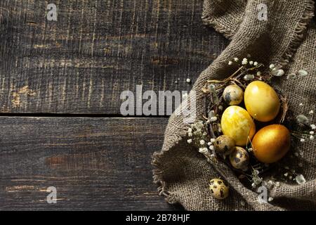 Golden easter eggs in nest and easter decoration on wooden table. Top view flat lay background. Copy space. Stock Photo