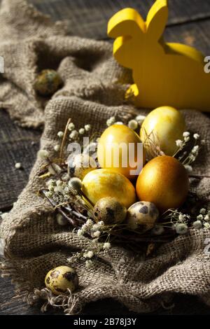 Easter eggs background. Golden easter eggs in nest and easter decoration on wooden table. Stock Photo