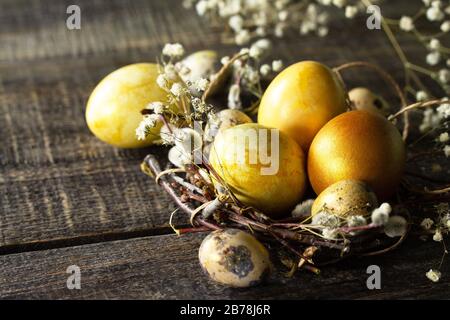 Golden easter eggs in nest and easter decoration on wooden table. Copy space. Stock Photo