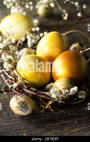 Easter eggs background. Golden easter eggs in nest and easter decoration on wooden table. Stock Photo