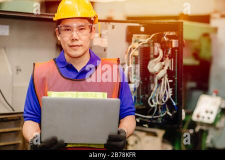 Portrait of service engineer team working with electronic wire back panel of heavy industry machine for maintenance repair and fix with laptop compute Stock Photo