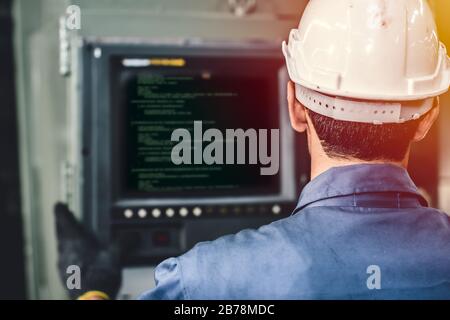 worker operate CNC machine with G-Code monitor, high skill labor work industry with safety clothes. Stock Photo