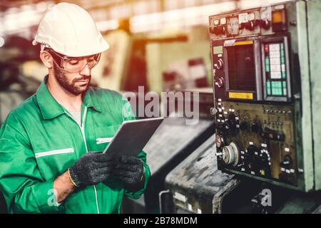 Green eco worker checking energy consumption engieer working in heavy industry factory with green colour safety suit. Stock Photo