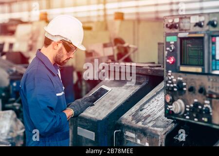 engineer setup the CNC machine with G-Code programming upload from Computer Tablet for technology in heavy industry. Stock Photo