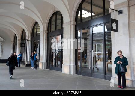 Members of staff stand outside of the Apple Store in Covent Garden, London, as they tell customers that the shop is shut. Apple is closing all stores outside Greater China until March 27 in response to the coronavirus pandemic. Stock Photo