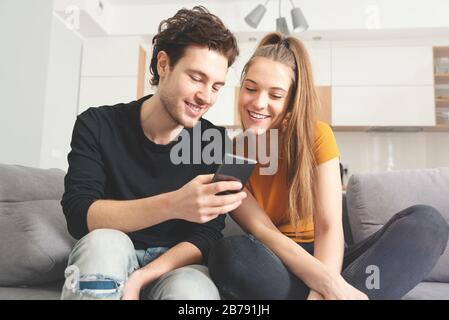 Couple using fast home internet with smart phone. Woman and man using social media. Stock Photo