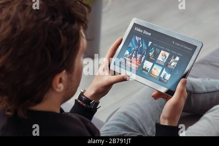Man using tablet for watching VOD service. Video On Demand television concept Stock Photo