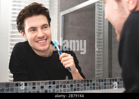 Man brushing teeth in bathroom. Dental health concept Stock Photo
