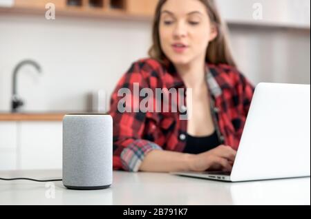 Woman talking to smart speaker. Intelligent assistant in smart home system. Stock Photo
