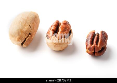 Set of three pecans in the center in a shell, peeled and without a shell isolated on a white background in a row. Close-up, top view Stock Photo