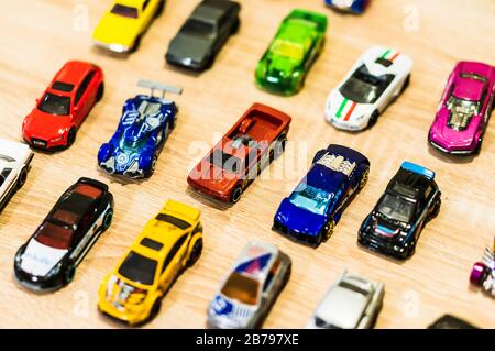 POZNAN, POLAND - Feb 27, 2020: Mix of different Mattel Hot Wheels toy cars on a wooden surface in soft focus. Horizontal high angle view. Stock Photo