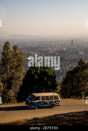 Bus passing in front of a panoramic view of the town seen from Entoto mountain, Addis Ababa Region, Addis Ababa, Ethiopia Stock Photo