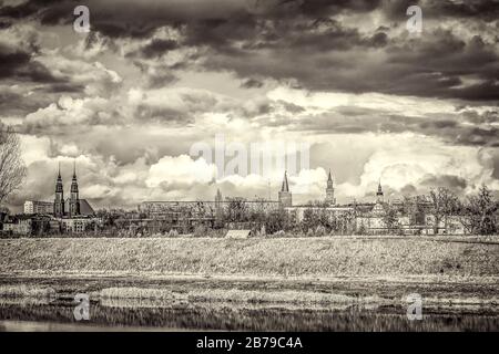 Grayscale shot of buildings in the distance under a cloudy sky Stock Photo