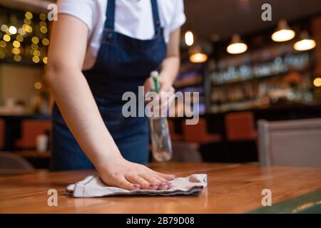 Hand of young contemporary waitress wiping wooden table with duster and detergent in the end of working day Stock Photo
