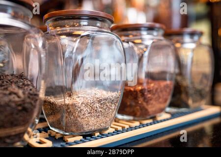 Row of big jars with fresh black, white, green and rooibos tea assortment standing on shelf in contemporary cafe or restaurant Stock Photo