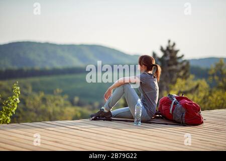 young female sitting on viewpoint high in mountain, looking at distance. nature, relaxing, filling with energy concept Stock Photo