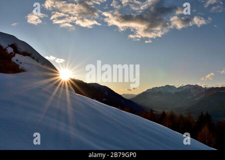 View of Valtellina from Campelli. The sun is going down behind the mountians, reflecting on the fresh snow Stock Photo
