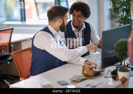 Creativity at work. Two smiling businessman at creative office listening music and working. Stock Photo