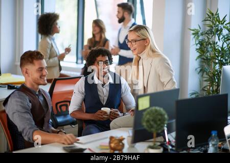 Business people having coffee break at work. Cheerful young colleagues sitting and smiling at workplace together.Communication concept Stock Photo