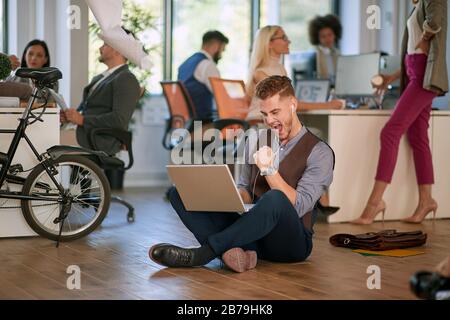 Happy and successful modern man of business startup team are looking on monitor of laptop after finish of great project. Stock Photo
