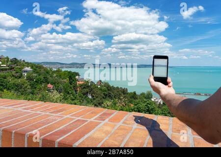 Tourist taking picture with his phone from Tihany abbey about one of the most beautiful view of the Lake Balaton Stock Photo