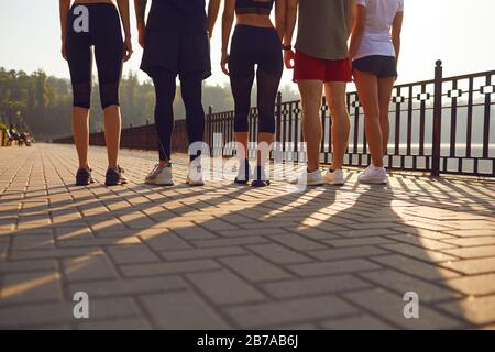 A group of young people runs along the road in the park. Stock Photo