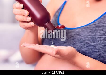 Pregnant woman applying body lotion on the hand. Stock Photo
