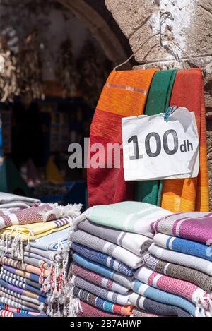 Vibrant fabrics, textiles, carpets and cushions for sale in the sunny souks of Essaouira, Morocco Stock Photo