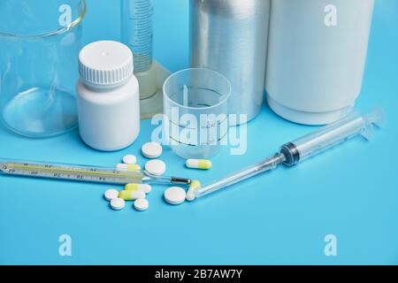 Thermometer with pills jars on a blue background. Close up. Stock Photo