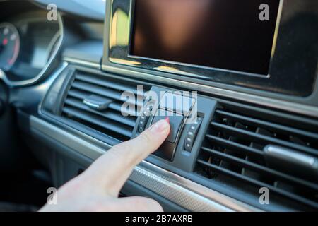 A man in a modern car. Hand presses the emergency button to turn on the alarm. Close up. Stock Photo