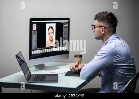 Side view of a casual male photo editor using graphics tablet in a bright office Stock Photo