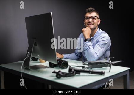 Young man sitting at table with different devices and gadgets at his office Stock Photo