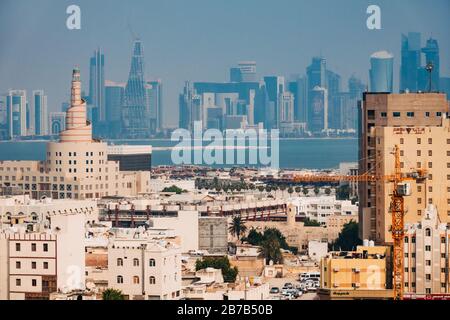 The famous spiral mosque of the Kassem Darwish Fakhroo Islamic Centre near Souq Waqif in Doha, Qatar. The city skyline can be seen behind in the haze Stock Photo