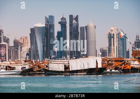 Dhow boats parked at Dhow Harbour with the financwial centre skyline visible behind, one summer morning in Doha, Qatar Stock Photo