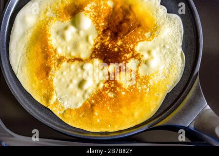 pancake frying pan with crepe pancake cooking on cooker in kitchen Stock Photo