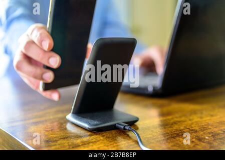 man charging smartphone using Wireless charging stand at home office Stock Photo