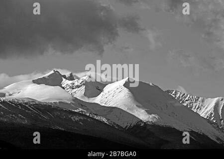 Winter Landscape with rugged Peaks and storm clouds over Mountain Range and forest wilderness.. Stock Photo