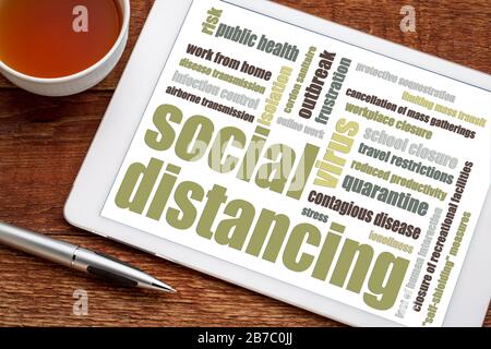 Social distancing word cloud on tablet - a set of nonpharmaceutical infection control actions to stop or slow down the spread of a contagious disease. Stock Photo