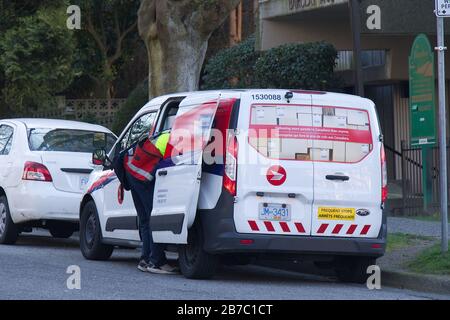 Vancouver, Canada - February 20, 2020: A Canada Post employee sorts packages inside the Canada Post Van in Downtown Vancouver Stock Photo