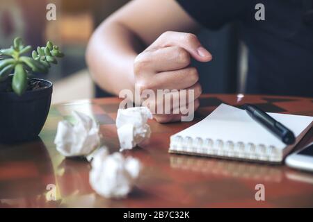 Closeup image of a businesswoman upset and screwed up papers on table with notebook and mobile phone Stock Photo