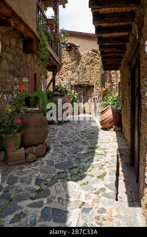 The view of the narrow stone paved sade street of the old Kakopetria lined by flowers in the pots.  Nicosia District. Cyprus Stock Photo