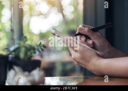 Closeup image of a businesswoman's hand working and holding a white blank notebook with screwed up papers on table Stock Photo