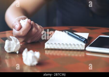 Closeup image of a businesswoman screwed up papers on table with notebook and mobile phone Stock Photo