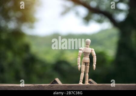 Closeup image of wooden figure model of a man standing on wooden table with blur background Stock Photo