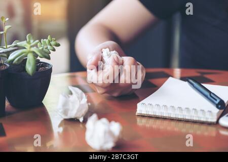Closeup image of a businesswoman screwed up papers on table with notebook and mobile phone Stock Photo