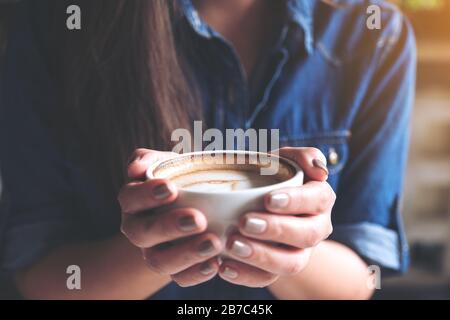 Closeup image of a woman holding a cup of coffee before drinking with feeling good and relaxed  in cafe Stock Photo