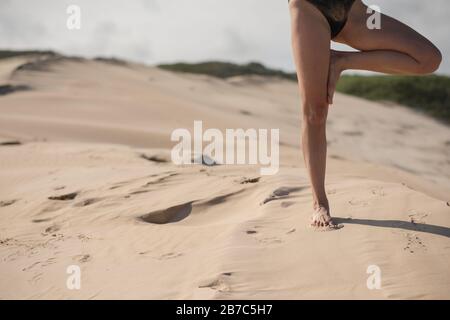 Woman doing a yoga pose on sand dune Stock Photo