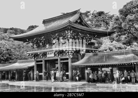 Tokyo, Japan - 31 December 2020: Buiddhist temple complex Meiji-jingu in the middle of green park. Entry gate around inner yard at rain with tourists Stock Photo