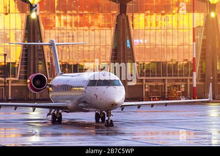 Airplane at the airport in front of the terminal during sunset Stock Photo